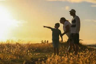 man and woman holding hands while walking on grass field during sunset by Luemen Rutkowski courtesy of Unsplash.