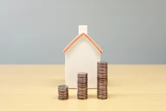 a house and stacks of coins on a table by Artful Homes courtesy of Unsplash.