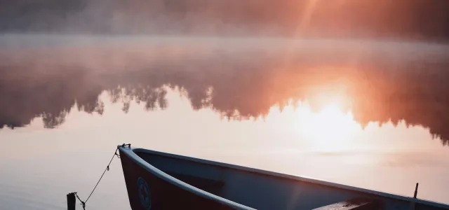 white and black boat on water during sunset by dominik hofbauer courtesy of Unsplash.