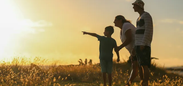 man and woman holding hands while walking on grass field during sunset by Luemen Rutkowski courtesy of Unsplash.