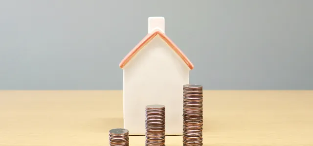 a house and stacks of coins on a table by Artful Homes courtesy of Unsplash.